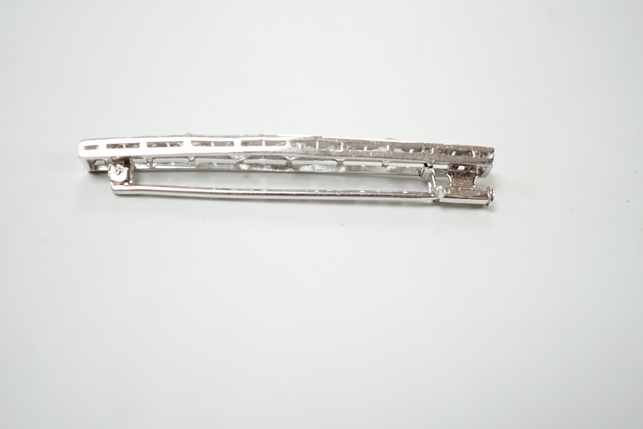 A 1920's/1930's white metal and graduated nine stone diamond set bar brooch, 48mm, gross weight 4.6 grams.